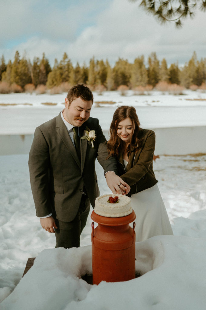 couple cutting the wedding cake in the snow